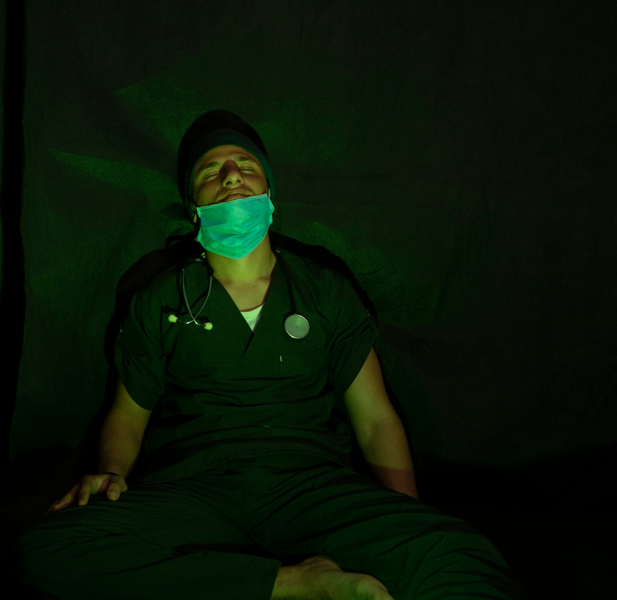 man in black button up shirt and black pants sitting on black textile